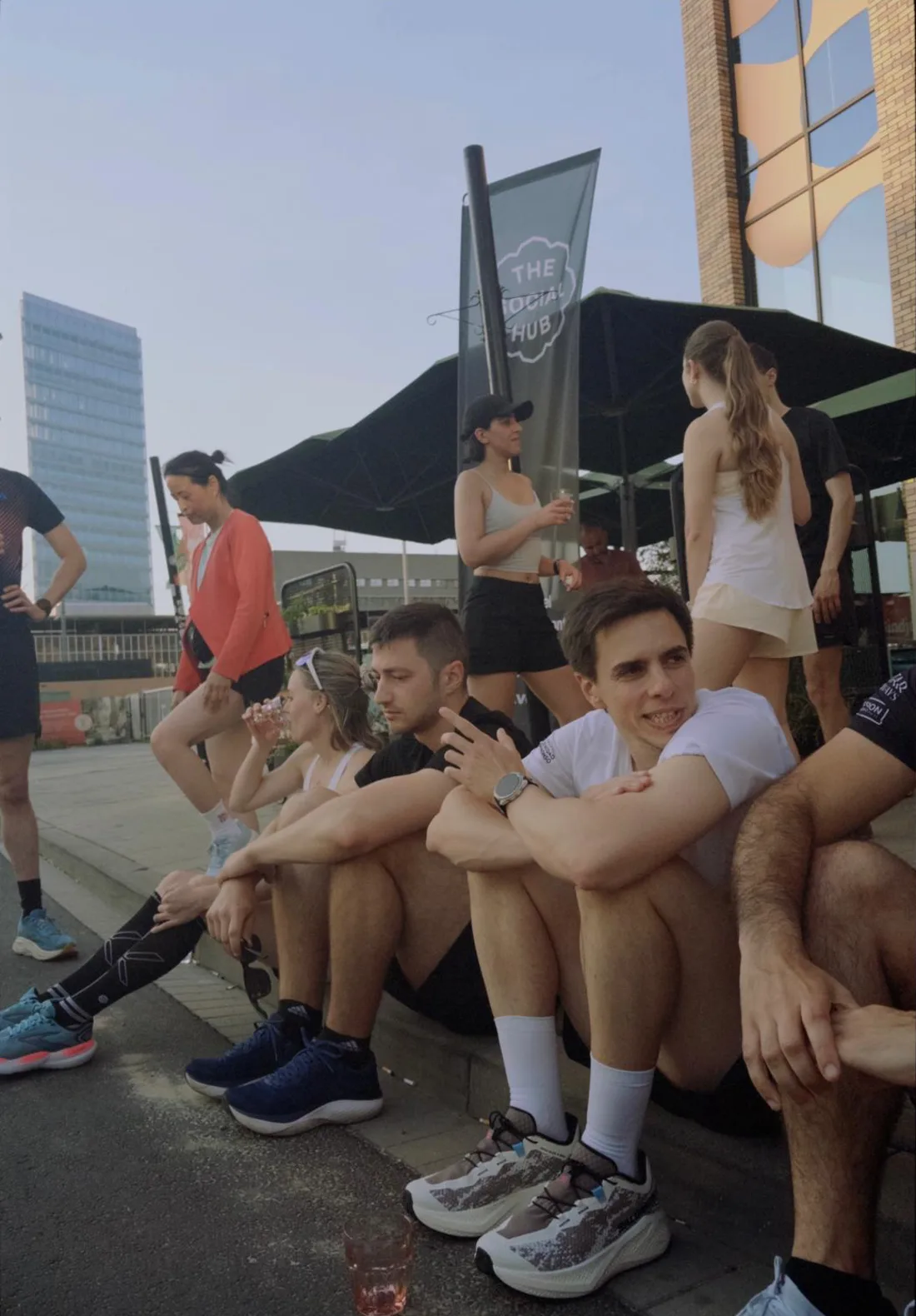 Lightmile runners resting together on a curb at golden hour after a run