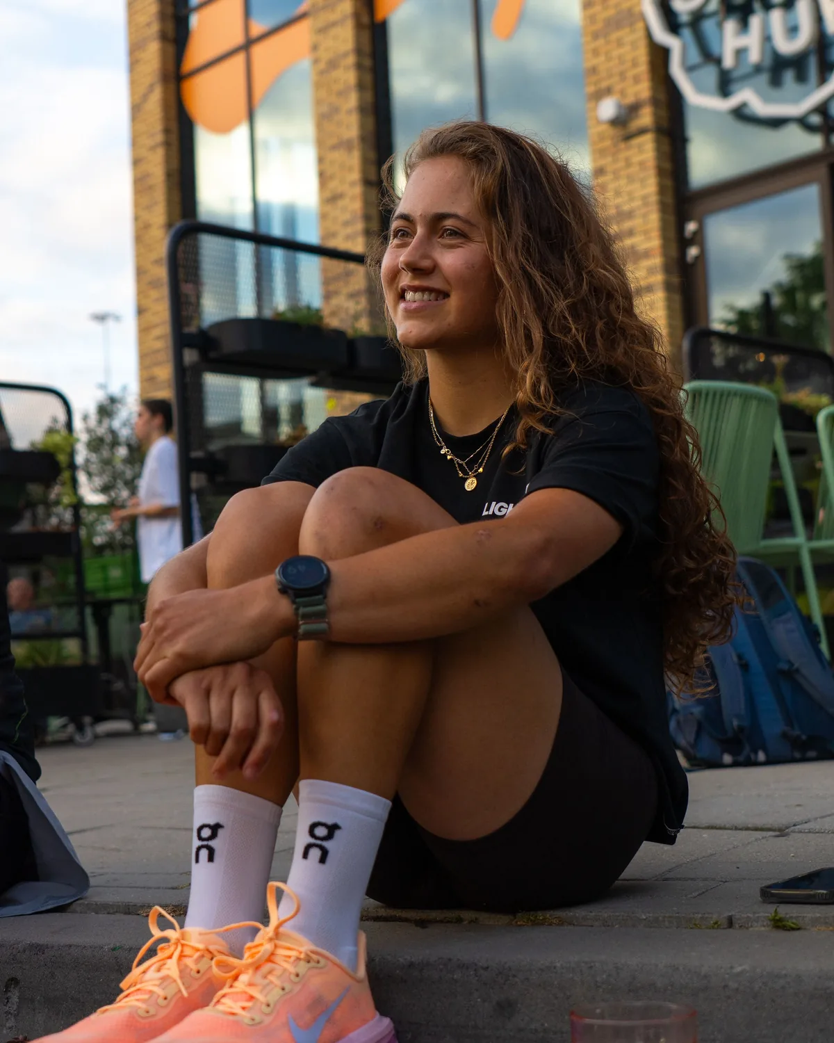 Ana sitting on the curb outside The Social Hub after a run
